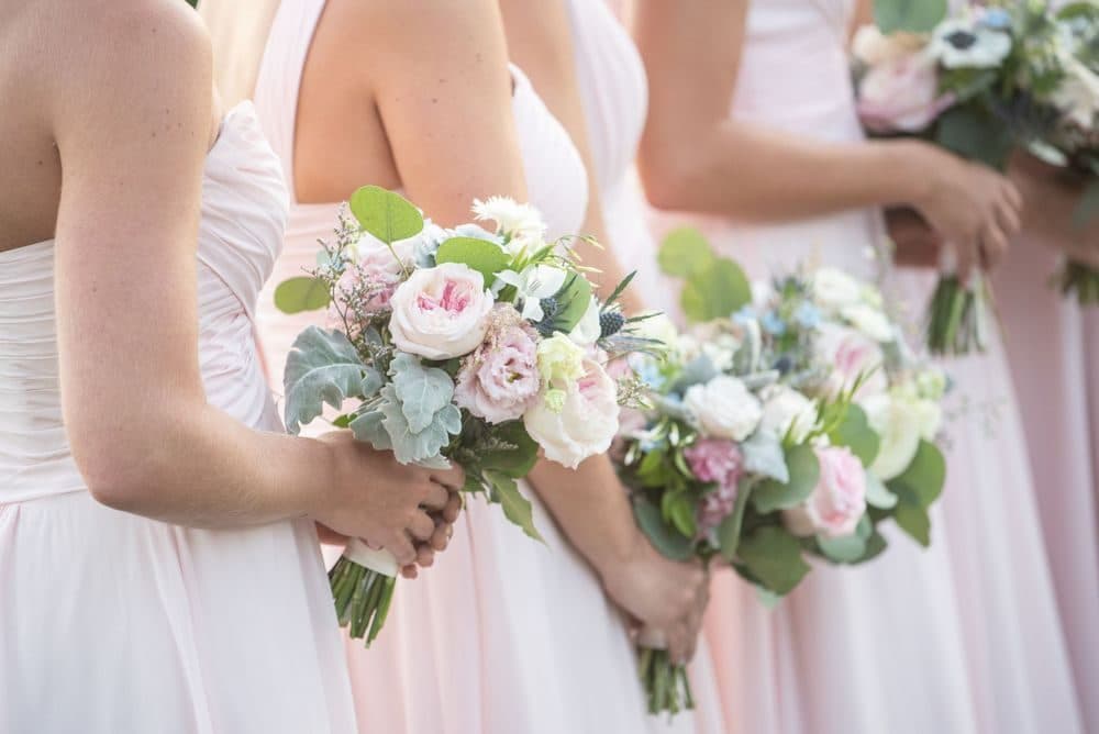 Bridesmaids in blush pink dresses holding white and blush bouquets