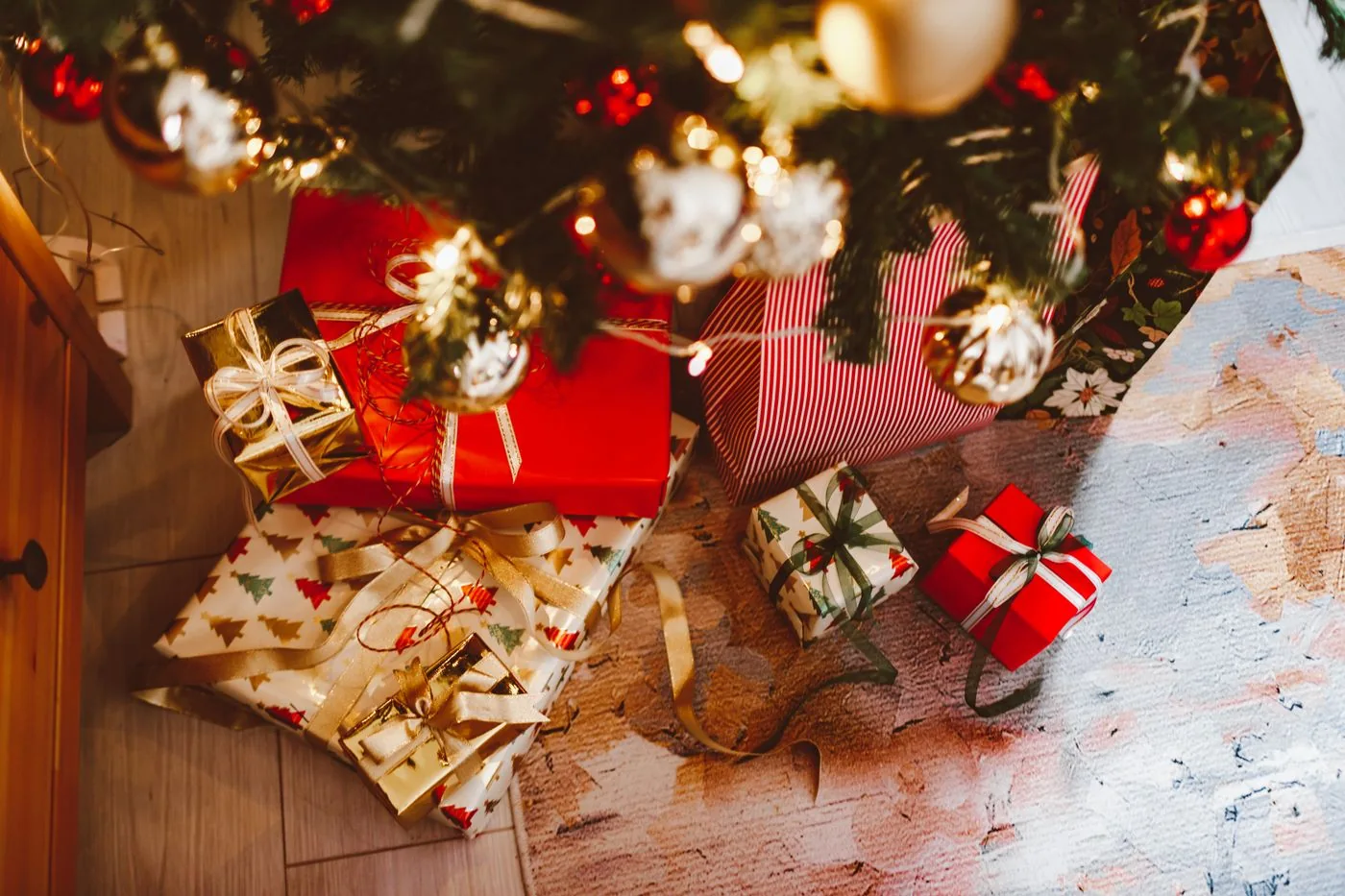 Wrapped Christmas gifts beneath an ornament-filled Christmas tree